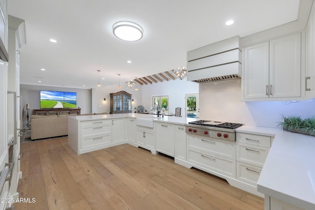 kitchen featuring white cabinets, decorative light fixtures, kitchen peninsula, and stainless steel gas stovetop