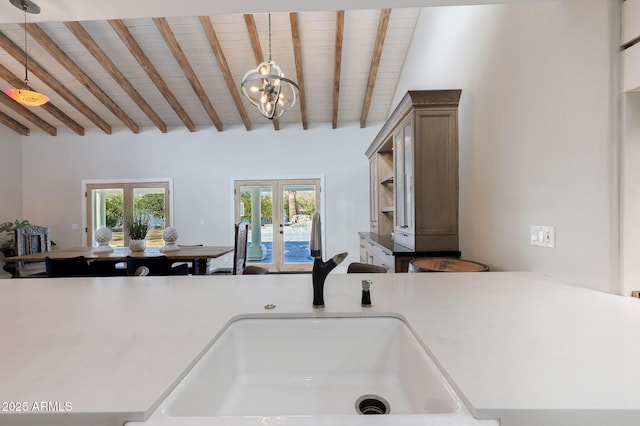 kitchen featuring hanging light fixtures, beamed ceiling, kitchen peninsula, and french doors