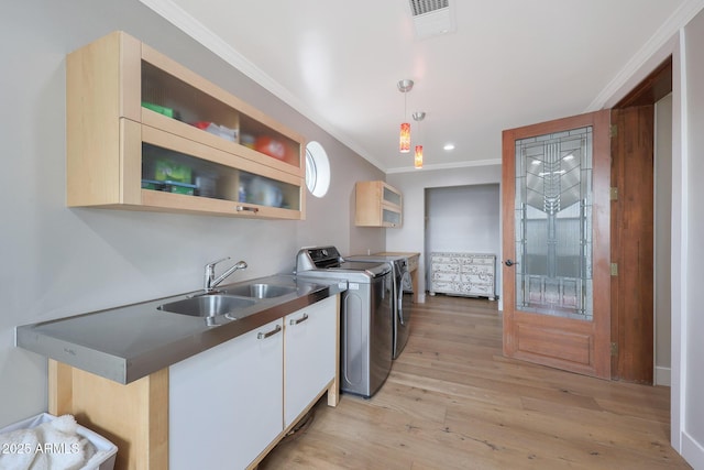 kitchen featuring sink, ornamental molding, a kitchen bar, separate washer and dryer, and decorative light fixtures