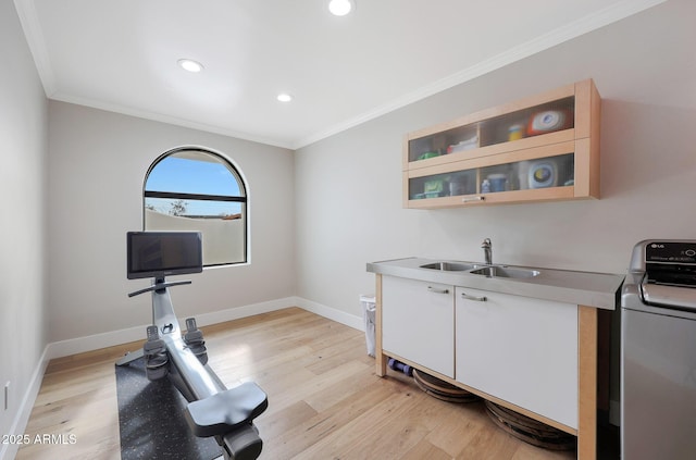 exercise room with crown molding, washer / dryer, sink, and light wood-type flooring