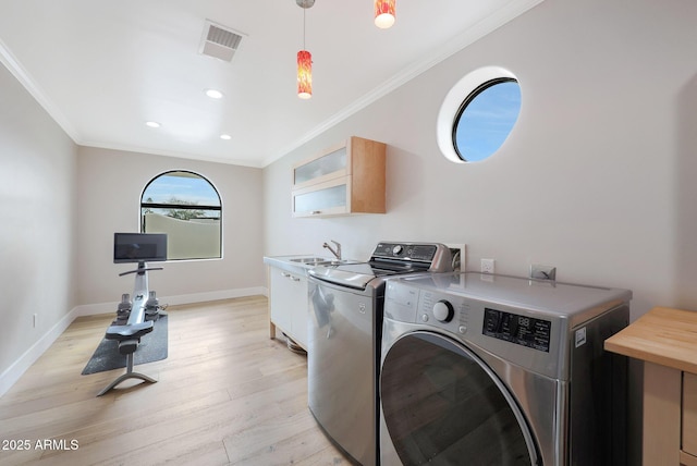 laundry area with ornamental molding, separate washer and dryer, sink, and light hardwood / wood-style floors