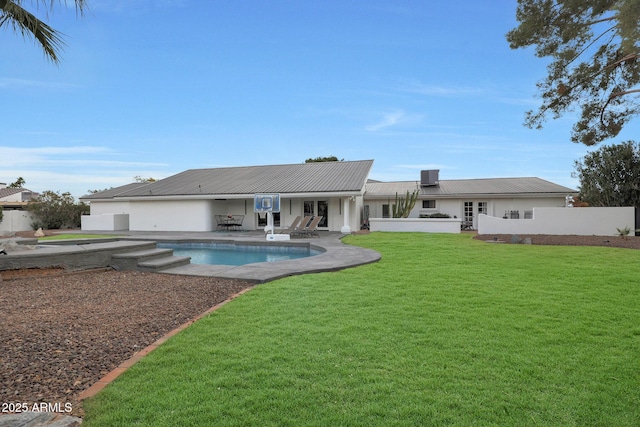 rear view of property featuring a yard, a fenced in pool, and a patio area