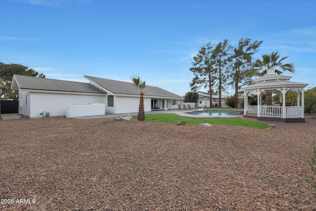 back of property featuring a fenced in pool, a gazebo, and a patio