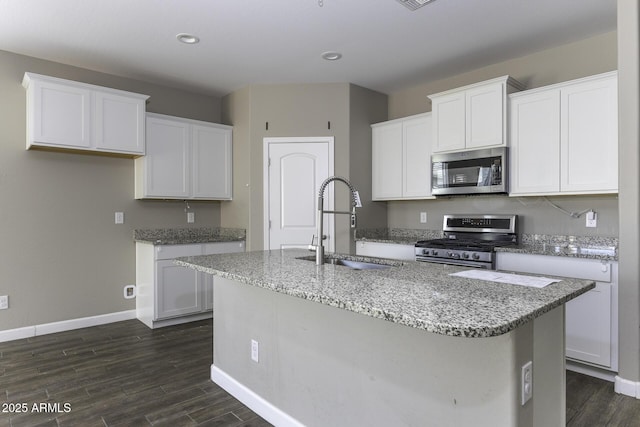 kitchen featuring appliances with stainless steel finishes, white cabinetry, sink, dark hardwood / wood-style flooring, and a kitchen island with sink