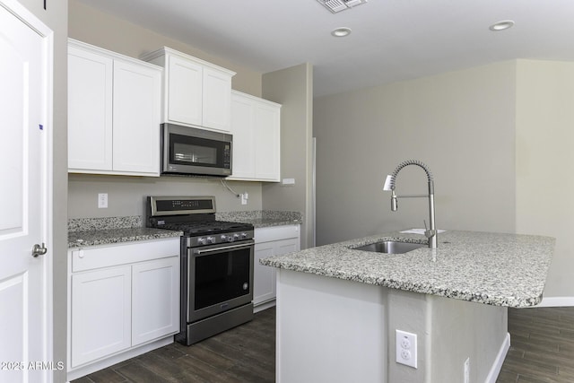 kitchen featuring sink, white cabinets, stainless steel appliances, dark wood-type flooring, and a center island with sink