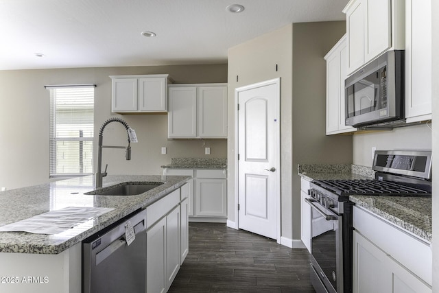 kitchen with stainless steel appliances, white cabinetry, sink, and stone counters