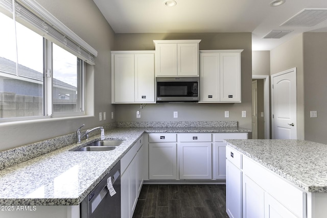 kitchen featuring light stone counters, dishwasher, sink, and white cabinets