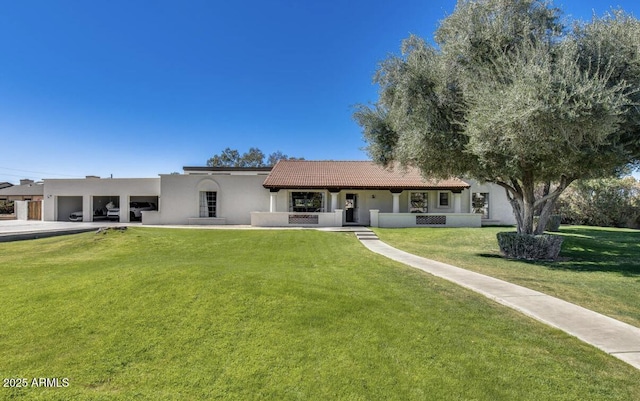 rear view of house featuring a garage, a tile roof, a lawn, and stucco siding