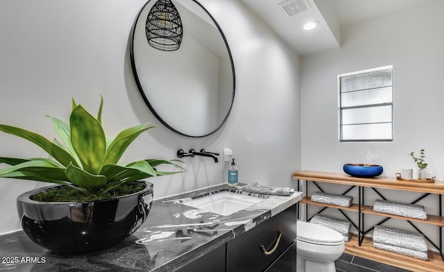 half bath with recessed lighting, visible vents, toilet, vanity, and wood finished floors