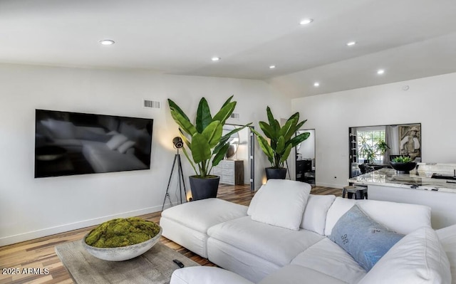 living room featuring lofted ceiling, wood finished floors, visible vents, and baseboards