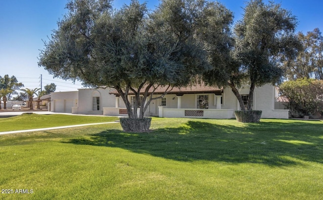 view of front of house with a front yard, an attached garage, and stucco siding