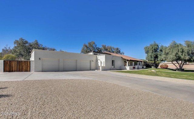 view of front of property featuring an attached garage, fence, concrete driveway, stucco siding, and a front yard