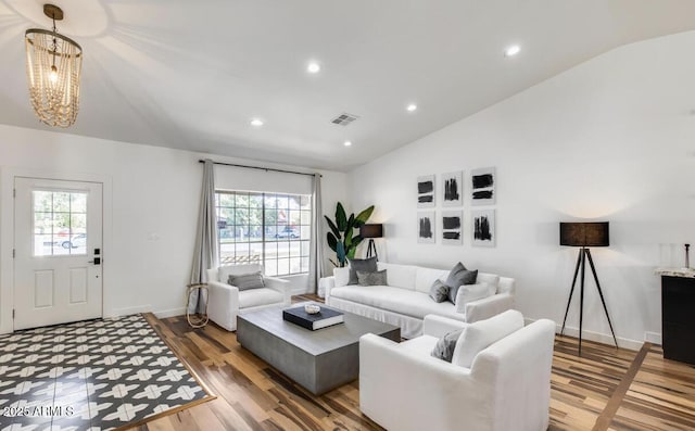 living room with a wealth of natural light, lofted ceiling, visible vents, and wood finished floors