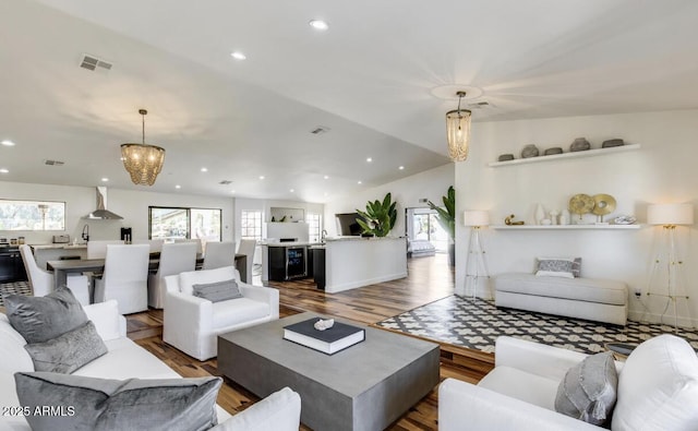 living area with a chandelier, a healthy amount of sunlight, visible vents, and wood finished floors