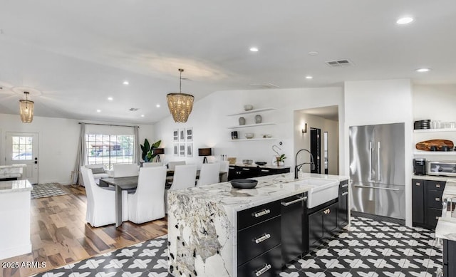 kitchen with visible vents, vaulted ceiling, a sink, dark cabinetry, and high end refrigerator