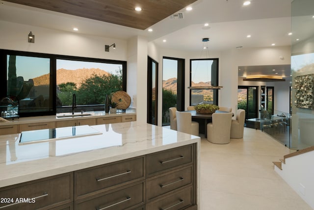 kitchen with a mountain view, sink, light stone counters, and decorative light fixtures