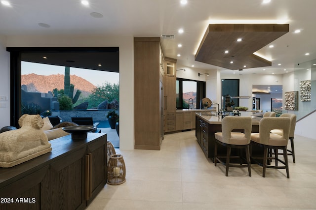 kitchen with a center island with sink, a mountain view, a healthy amount of sunlight, and a breakfast bar