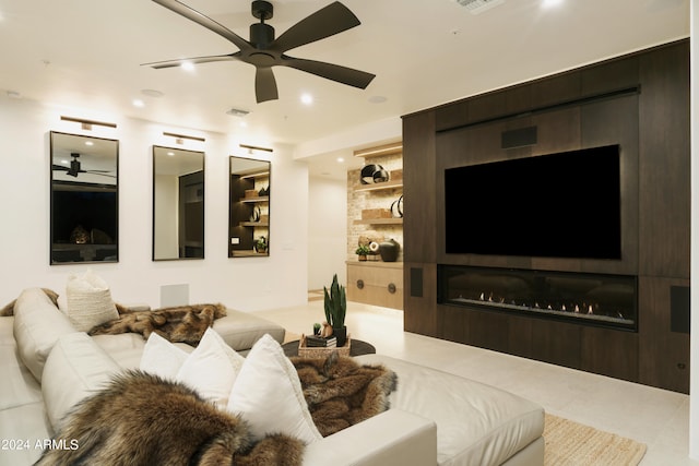 living room with tile patterned floors, ceiling fan, a large fireplace, and built in features