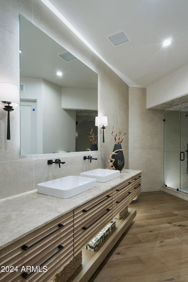 bathroom featuring vanity, an enclosed shower, wood-type flooring, and tile walls