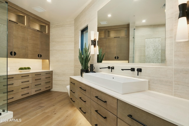 bathroom with walk in shower, hardwood / wood-style floors, toilet, vanity, and tile walls