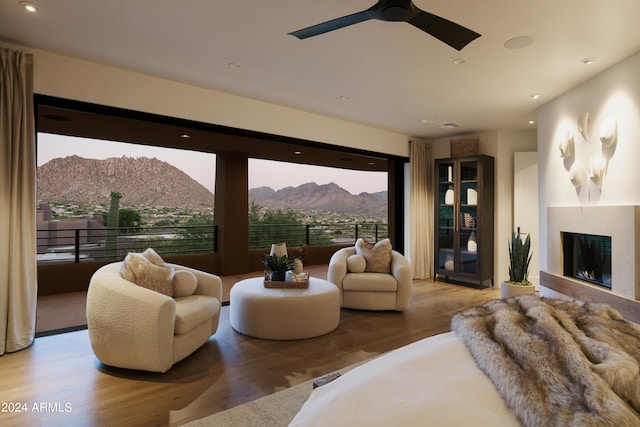 living room with a mountain view, light wood-type flooring, and ceiling fan