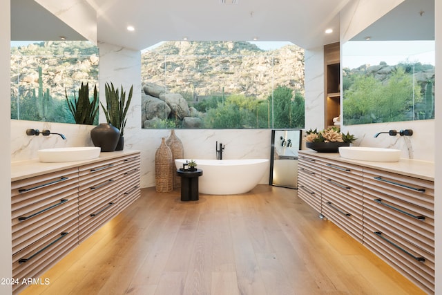 bathroom featuring hardwood / wood-style floors, a washtub, tile walls, and vanity