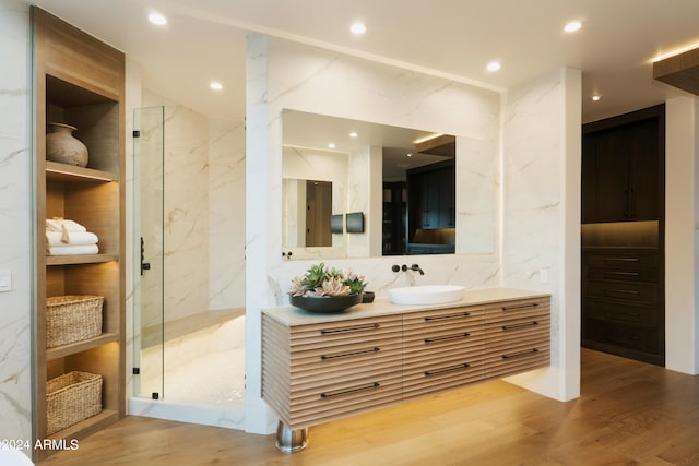 bathroom featuring decorative backsplash, wood-type flooring, vanity, and a shower with shower door