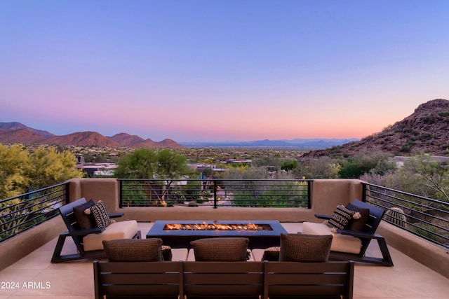 patio terrace at dusk featuring a mountain view and an outdoor living space with a fire pit