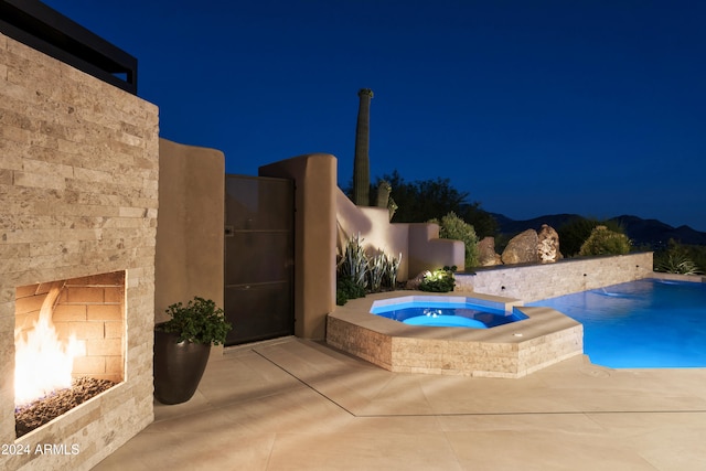 pool at night featuring an in ground hot tub and a mountain view