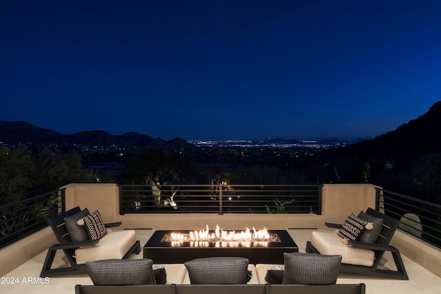 patio at night featuring a mountain view and an outdoor living space with a fire pit