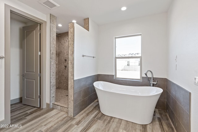 0000 W Hooper Trl Unit 3, Queen Creek, AZ 85144 - bathroom featuring a freestanding tub, visible vents, wood finished floors, a tile shower, and tile walls