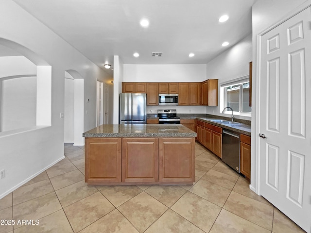 2971 N Rosewood Ave, Casa Grande, AZ 85122 - kitchen with appliances with stainless steel finishes, a sink, a kitchen island, arched walkways, and brown cabinetry
