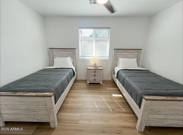 bedroom with light wood finished floors, visible vents, and a ceiling fan