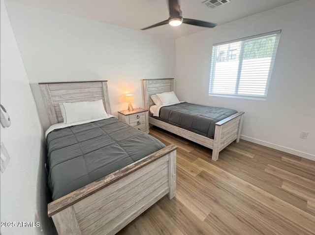 bedroom featuring light wood-style flooring, visible vents, baseboards, and a ceiling fan