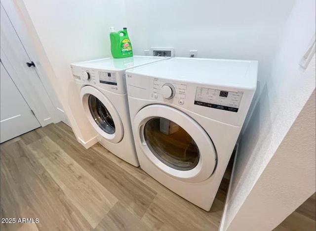 laundry room featuring laundry area, separate washer and dryer, and light wood-style flooring