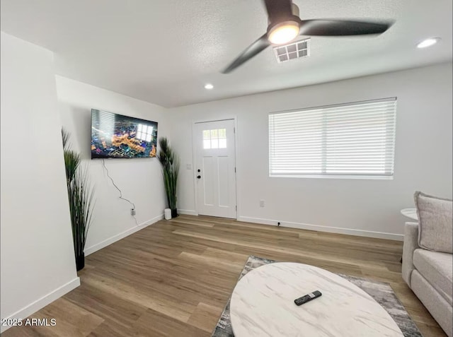 entrance foyer featuring visible vents, ceiling fan, baseboards, and wood finished floors