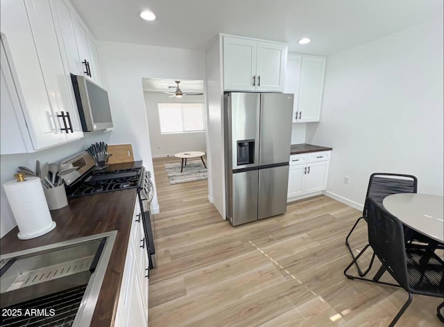 kitchen featuring recessed lighting, wooden counters, appliances with stainless steel finishes, light wood-style floors, and white cabinets