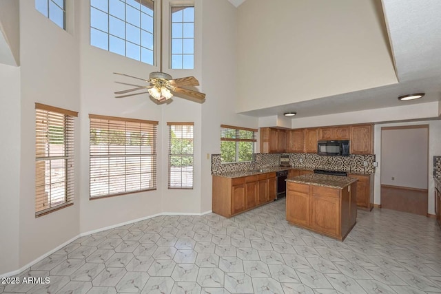6928 W Oraibi Dr, Glendale, AZ 85308 - kitchen featuring black appliances, brown cabinets, a towering ceiling, plenty of natural light, and a kitchen island