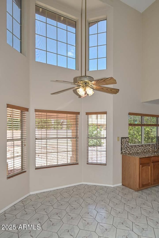 6928 W Oraibi Dr, Glendale, AZ 85308 - unfurnished living room with a high ceiling, a ceiling fan, and baseboards