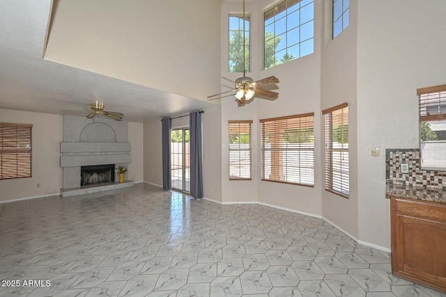 6928 W Oraibi Dr, Glendale, AZ 85308 - unfurnished living room with ceiling fan, a fireplace, baseboards, and a towering ceiling