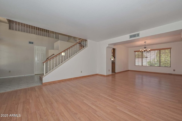 6928 W Oraibi Dr, Glendale, AZ 85308 - unfurnished living room featuring a chandelier, light wood-style floors, baseboards, and stairs
