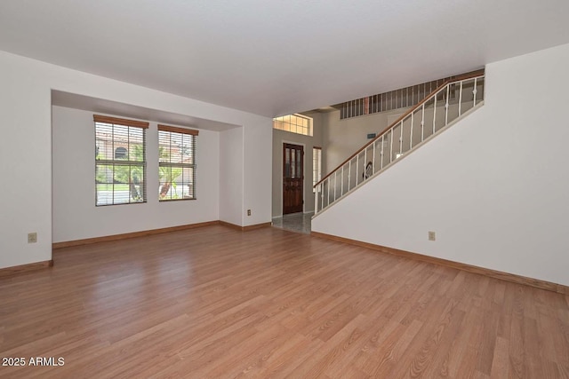 6928 W Oraibi Dr, Glendale, AZ 85308 - unfurnished living room featuring light wood-type flooring, baseboards, and stairway