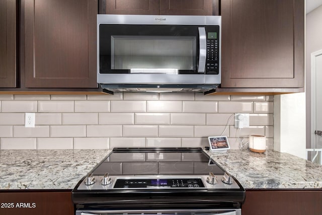 kitchen featuring light stone counters, decorative backsplash, dark brown cabinets, and appliances with stainless steel finishes