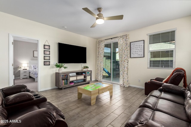 living area featuring a ceiling fan, baseboards, and wood tiled floor