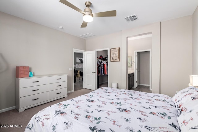 carpeted bedroom with visible vents, a walk in closet, ceiling fan, ensuite bathroom, and a closet