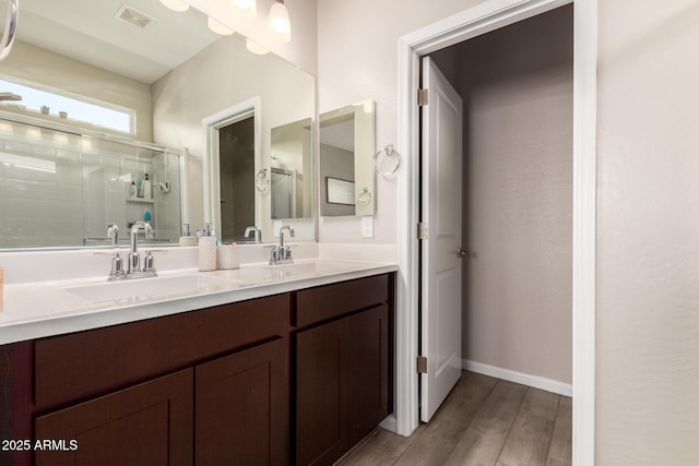 full bathroom with double vanity, visible vents, a shower stall, and a sink