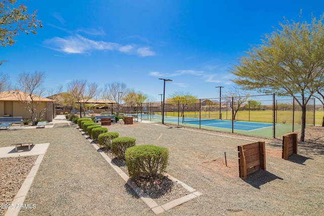 view of home's community with a tennis court and fence