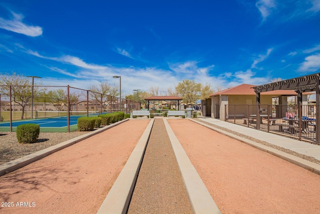 view of home's community with a tennis court and fence