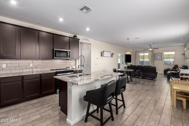 kitchen with a ceiling fan, visible vents, decorative backsplash, appliances with stainless steel finishes, and open floor plan