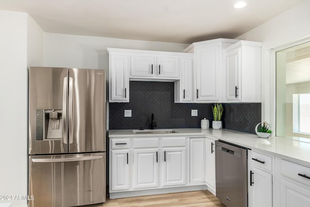 kitchen featuring light stone counters, stainless steel appliances, sink, light hardwood / wood-style flooring, and white cabinetry